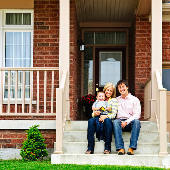 happy homeowners sitting on the stairs of their home's front entry way